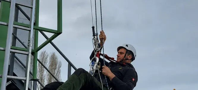 Курсист се спуска на въже покрай стълбата на учебната кула.
